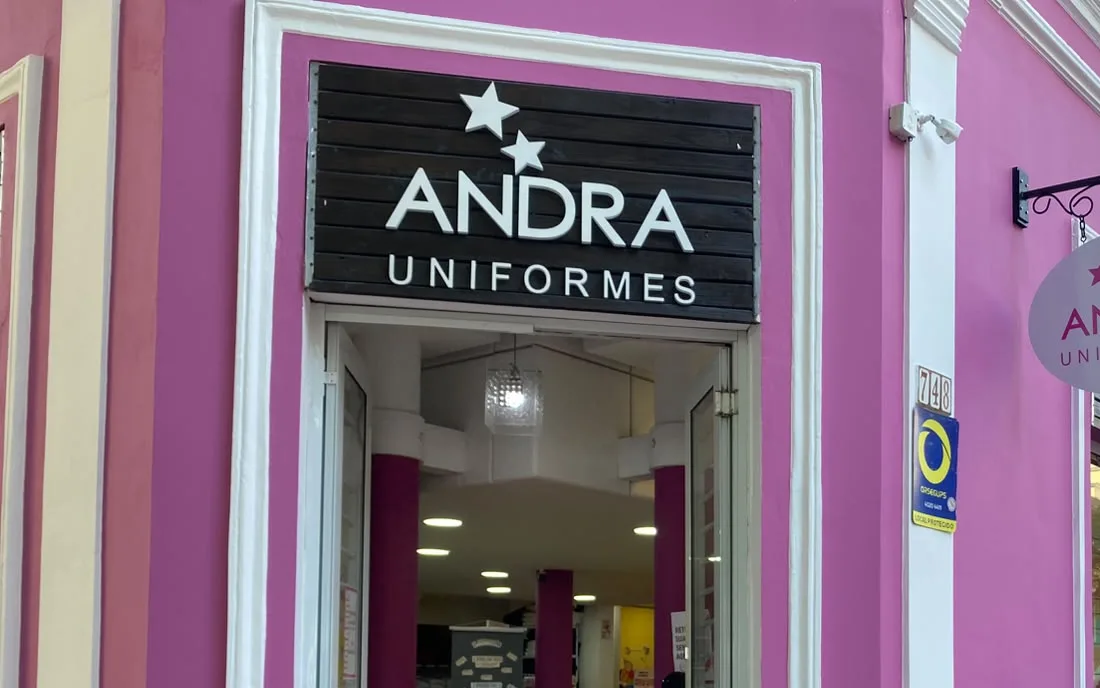 Entrada da loja Andra Uniformes, com a placa da marca sobre a porta