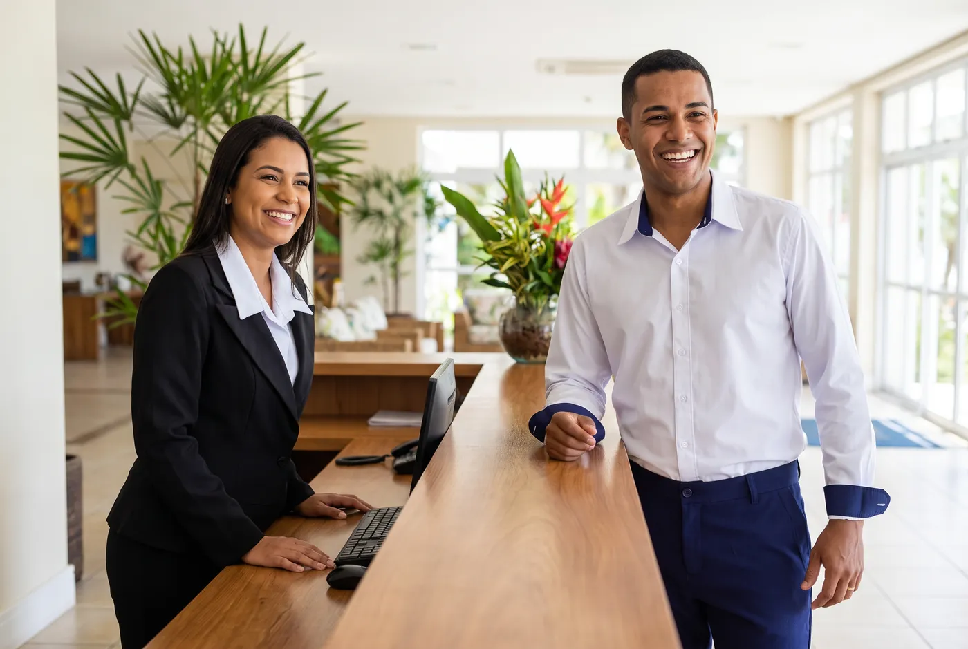 Recepcionistas de hotel uniformizados atrás do balcão da recepção